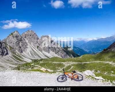 Mountainbike auf der Seite einer Geschotterten Straße in hohen Bergkette der Lienzer Dolomiten, Österreich liegen. Die Pisten sind unfruchtbar mit wenig Gras auf Sie. Stockfoto