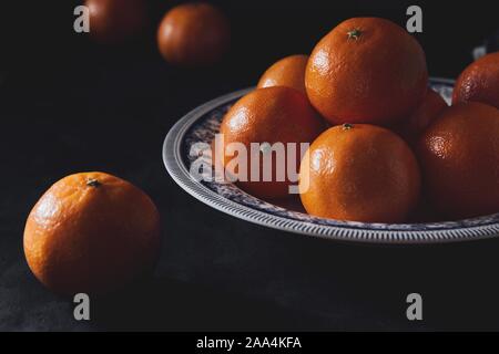 Mandarinen auf einem schwarzen Holztisch in eine rustikale Küche. Reife Früchte in einer dunklen Essen Fotografie mit der leere Raum. Stockfoto