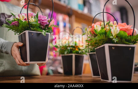 Florist Mädchen hält Strauß Blumen Rosen und gelben Chrysanthemen in Geschenkbox. Stockfoto