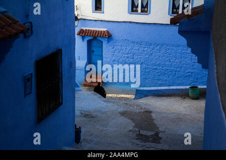 Ein Mann sitzt in einem der kreuzenden Straßen von Chefchauen "blaue Perle in den Bergen von Marokko im Herbst Saison. Stockfoto