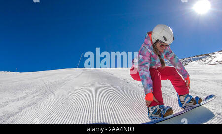 Ein snowboard Mädchen in rosa Hose und Helm eine perfekt präparierte Piste. Sie genießt die Fahrt, und die perfekte Bedingungen. Es ist n Stockfoto