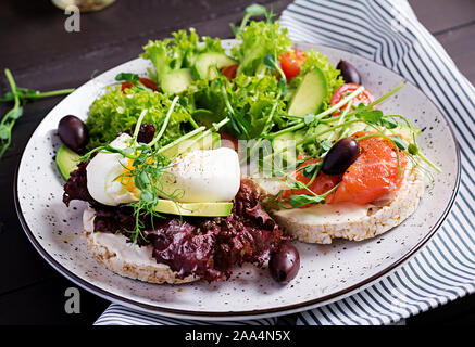 Gesundes Frühstück. Sandwiches mit Frischkäse, gekochtem Ei und geräuchertem Lachs, Avocado an der Platte. Stockfoto