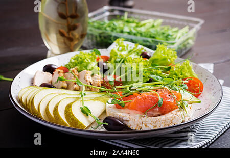 Gesundes Frühstück. Sandwiches mit Frischkäse, Lachs, Avocado und Scheibe Birne an der Platte. Stockfoto