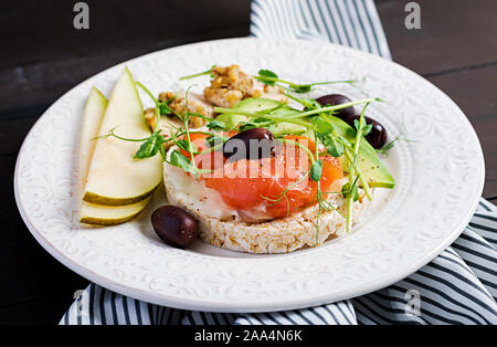 Gesundes Frühstück. Sandwiches mit Frischkäse, Lachs, Avocado und Scheibe Birne an der Platte. Stockfoto