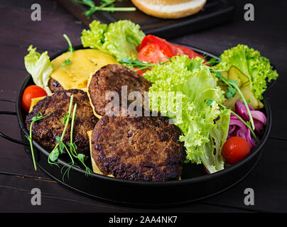Burger Kochen-Burger mit Rindfleisch, Tomaten, Käse, Gurken und Zwiebeln auf Platte Stockfoto