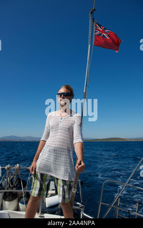 Mann an Deck Lenkung einer Yacht, Sardinien, Italien Stockfoto