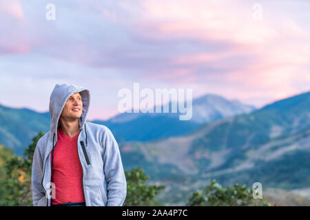 Aspen, Colorado bunte violett blau Dämmerung Sonnenuntergang verschwommenen Hintergrund Blick auf die Rocky Mountains und glückliche junge Mann in hoodie Pullover suchen Stockfoto