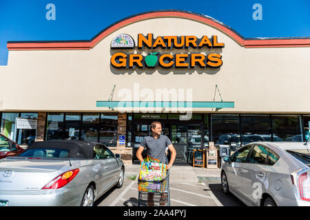 Durango, USA - 22. August 2019: Mann mit Warenkorb und Taschen mit Vorzeichen vor dem Eingang zu den natürlichen Lebensmittelgeschäft, Supermarkt, Parkplatz Stockfoto