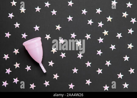 Rosa Menstruationsschale auf schwarzem Hintergrund mit einer Vielzahl von Sternen. Konzept Einsatzmöglichkeit Cup in der Nacht, null Abfall, Einsparungen, Minimalismus. Feminine Hygiene Stockfoto