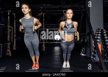 Zwei junge in voller Länge Sportler Training mit gespannten Gummiband in der Turnhalle Stockfoto