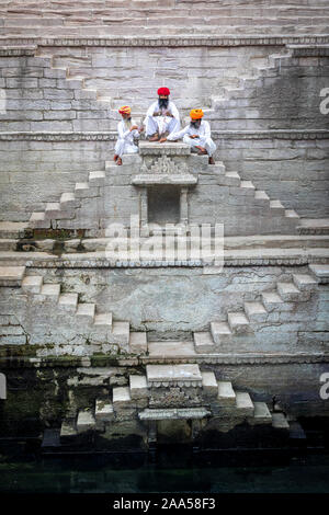 Drei Männer spielen Karten auf den Stufen der stepwell Toorji Ka Jhalra in Jodhpur, Rajasthan, Indien Stockfoto