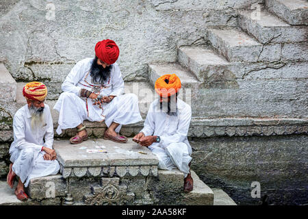 Drei Männer spielen Karten auf den Stufen der stepwell Toorji Ka Jhalra in Jodhpur, Rajasthan, Indien Stockfoto