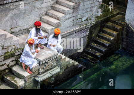 Drei Männer spielen Karten auf den Stufen der stepwell Toorji Ka Jhalra in Jodhpur, Rajasthan, Indien Stockfoto