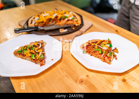 Hausgemachte warme Pizza Slices auf zwei Platten mit Tomatensauce und Toppings geschmolzen orange vegan Cheddar Käse servieren am Tisch Stockfoto