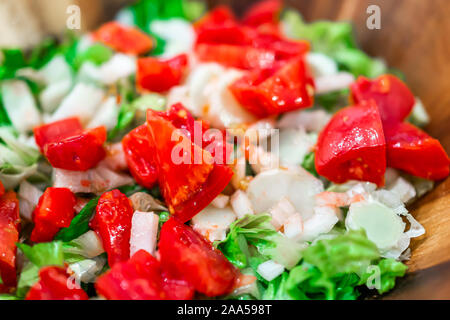 Gehacktes Gemüse in Houten Makro Nahaufnahme mit frischen vegan Salat mit Römersalat, Zwiebeln und leuchtendem Rot saftige heirloom Tomaten Stockfoto