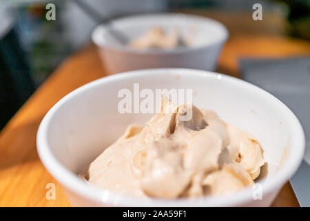 Weiche dienen Vanilleeis Schüsseln mit bokeh Hintergrund der Tabelle und Laptop mit Banane schön Creme vegan Dessert gemacht Stockfoto