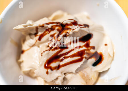 Weiche Vanilleeis Makro Nahaufnahme in der Schüssel von Banane schön Creme vegan Dessert dienen und Balsamico Essig beträufelt Sirup oder Schokoladensauce Stockfoto