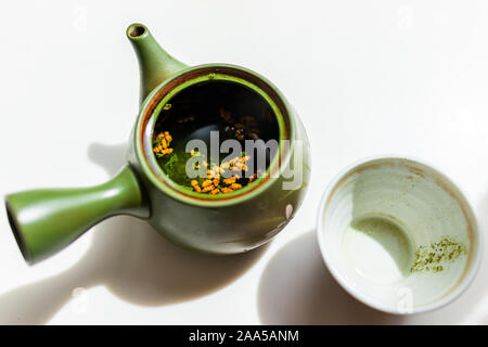 Grüner Ton Teekanne auf weißem Hintergrund mit leeren verwendet Tasse Tee in Japan mit kyusu Griff brauen genmaicha während der Zeremonie offenen Deckel mit gerösteten Ri Stockfoto