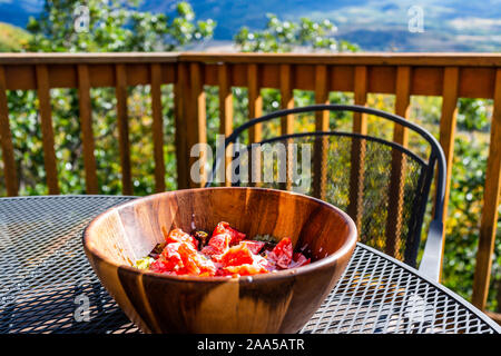 Tomatensalat in große hölzerne Schüssel auf Balkon Terrasse Tisch im Garten draußen in Aspen, Colorado mit Stuhl und niemand Stockfoto