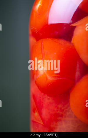 Eingelegte Tomaten in einer Marinade, in einem Glas auf einem Holztisch. Nahaufnahme Stockfoto