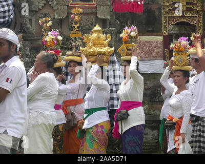 In Ubud, Indonesien - März, 14, 2018: Die hinduistischen Frauen und Männer mit Opfergaben an Tempel in Ubud, Bali Stockfoto