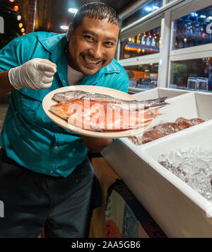 San Pedro, Ambergris Caye, Belize-November 16, 2019: ein belizean Restaurant Mitarbeiter anzeigen ein Teller ungekocht ganze hogfish und Black Snapper. Stockfoto