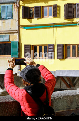 11 November 2019 - Florenz, Italien: Chinesische Touristen ausrichten, um ein Foto von der berühmten Ponte Vecchio mit ihren Smartphones zu nehmen. Stockfoto