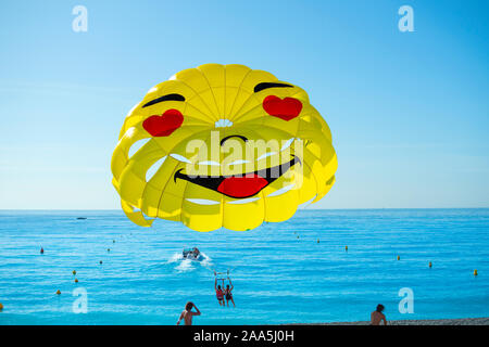 Ein Smiley parasail Fallschirm zieht aus der Strand hinter einem Motorboot an der französischen Riviera in Nizza, Frankreich Stockfoto