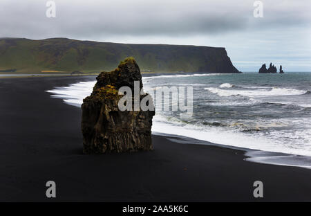 Arnardrangur "Eagle Rock'im Hintergrund Reynisdragar Felsformationen an Reynisfjara schwarzer Sandstrand Küste des Atlantischen Ozean in der Nähe von Dorf Vik, Stockfoto
