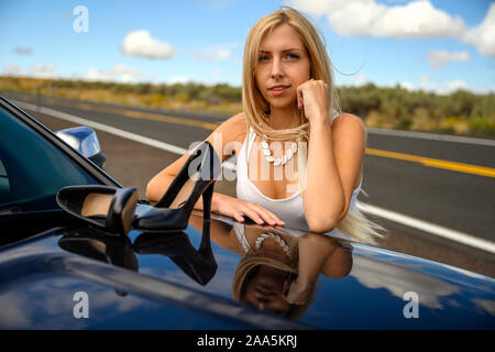 Absolute Freiheit. Hübsche junge Frau angehalten, ihr Auto in der Mitte von Nirgendwo, nahm ihr High Heel Schuhe aus und setzen Sie sie auf die Motorhaube und takin Stockfoto