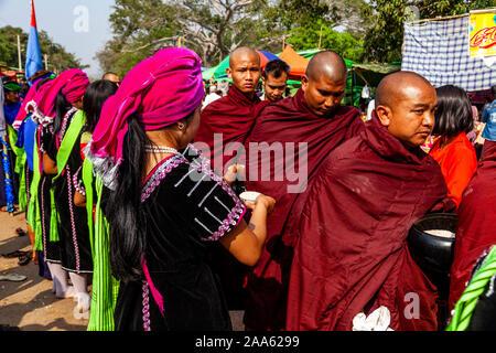 Eine Gruppe junger Frauen, die ethnischen Minderheiten angehören, Almosen/Spenden an lokale Buddhistische Mönche Im Pindaya Cave Festival, Pindaya, Shan Staat, Myanmar. Stockfoto