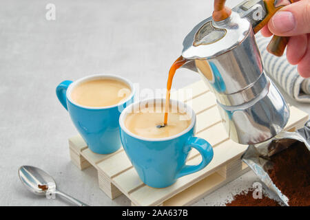 Kaffee gießen in Blau Becher von italienischen Kaffee Espressomaschine. Zwei Kaffeetassen und Espressokocher. Stockfoto