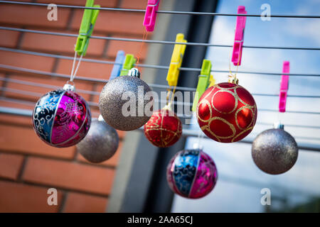 Weihnachtskugeln Ornamente hängen auf der Clips auf dem Wäscheständer. Weihnachten mit Hausarbeit. Stockfoto