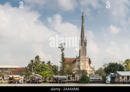 Cai, Mekong Delta, Vietnam - März 13, 2019: Entlang der Kinh 28 Kanal. Katholische Kirche, Nha Tho, mit beige Stein lange schlanke clock Spire und Madonna s Stockfoto