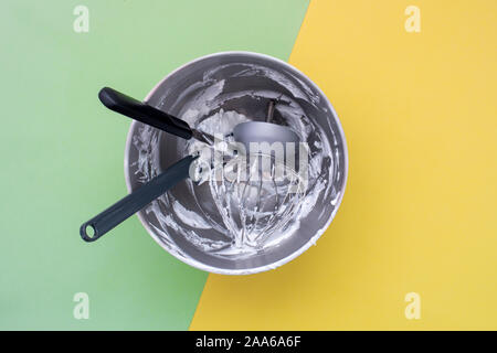 Backen Geschirr in mixer Schüssel nach Kuchen machen auf flache grüne gelben Hintergrund legen Stockfoto