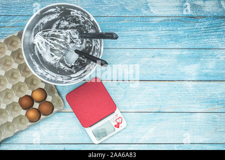 Flach, Kuchen backen, Besteck, rohe Eier und Zubehör auf Blau rustikal Hintergrund Stockfoto