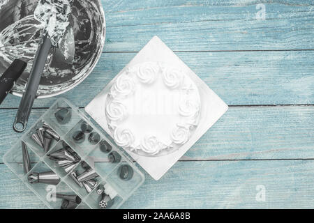 Kuchen backen Werkzeuge im Mixer Schüssel nach Kuchen Glasur, und ein Feld der Düsen auf Flach rustikalen blauer Hintergrund Stockfoto