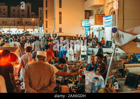 Kunden durchsuchen Artikel im Souq Al-Haraj, einem Markt, wo Verkäufer Kleidung und verschiedene Haushaltsgeräte in der Straße Stände in Doha, Katar Hektik Stockfoto