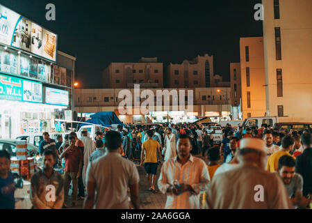 Menschenmassen Spaziergang durch Souq Al-Haraj, wo Verkäufer Kleidung und verschiedene Haushaltsgeräte in der Straße Stände Hektik in Doha, Katar Stockfoto