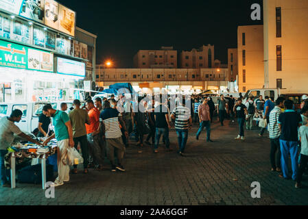 Kunden durchsuchen Artikel im Souq Al-Haraj, einem Markt, wo Verkäufer Kleidung und verschiedene Haushaltsgeräte in der Straße Stände in Doha, Katar Hektik Stockfoto