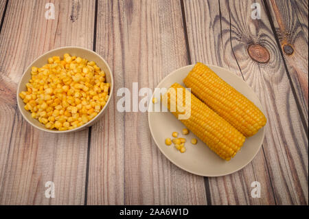 Zwei Ohren von gekochten Mais in eine Platte und ein Korn von Korn auf dem Tisch. Gesunde Ernährung. Fitness Ernährung. Für einen süßen Leckereien Stockfoto