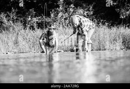 Männer sitzen am Flußufer mit Angelausrüstung. Wilderer angeln. Die wilderei Kriminalität und Lizenz. Schwarzmarkt Kaviar. Die illegale Jagd Kaviar. Auszüge Eier vom Stör gefangen. Trap für Fische. Stockfoto