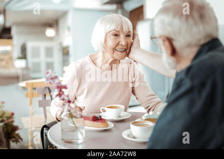 Schönes alter Mann seine wifes Wange berühren Stockfoto