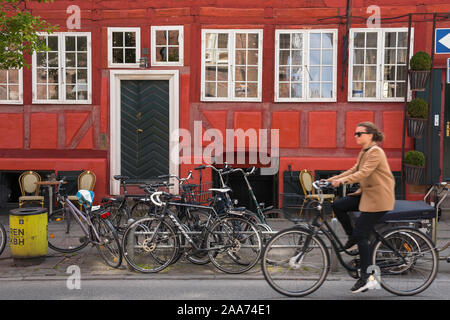 Kopenhagen Stadt, Ansicht im Sommer eine junge Frau mit dem Fahrrad durch die farbenfrohe Altstadt Quartier Latin im Zentrum von Kopenhagen, Dänemark. Stockfoto