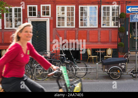 Kopenhagen, Dänemark, im Sommer eine junge Frau mit dem Fahrrad durch die bunte Altstadt von Zentrum von Kopenhagen, Dänemark. Stockfoto