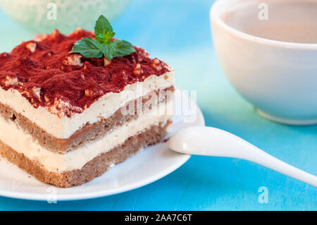Dessert Tiramisu tiramDessert dekoriert mit Minze auf einem blauen backgroundisu dekoriert mit Minze auf einem blauen Hintergrund Stockfoto