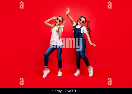 Volle Länge Foto von zwei hübschen Damen für lange Schwänze in der Schule Party die besten Freunde tragen cool Sun specs Jeans overall weißes T-shirt Freude Stockfoto