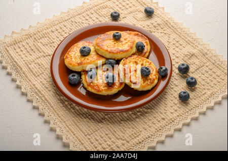 Hausgemachter Käsekuchen auf einem Teller mit Beeren und Sirup. Gesunde Ernährung Stockfoto