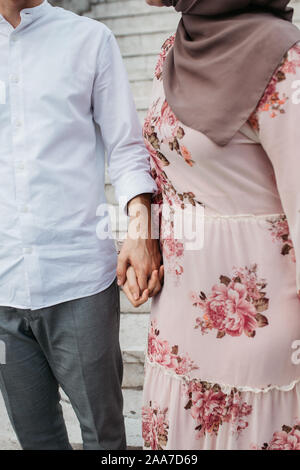 Nahaufnahme der junge Paar Hand in Hand. Liebe und Partnerschaft Ziele. Der Mann und die Frau zu Fuß auf die Straße. Stockfoto