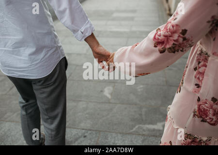 Nahaufnahme der junge Paar Hand in Hand. Liebe und Partnerschaft Ziele. Der Mann und die Frau zu Fuß auf die Straße. Stockfoto